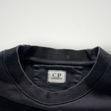 Gros plan sur le col rond en coton noir du sweat-shirt Secondstore C.P. COMPANY avec étiquette de marque visible