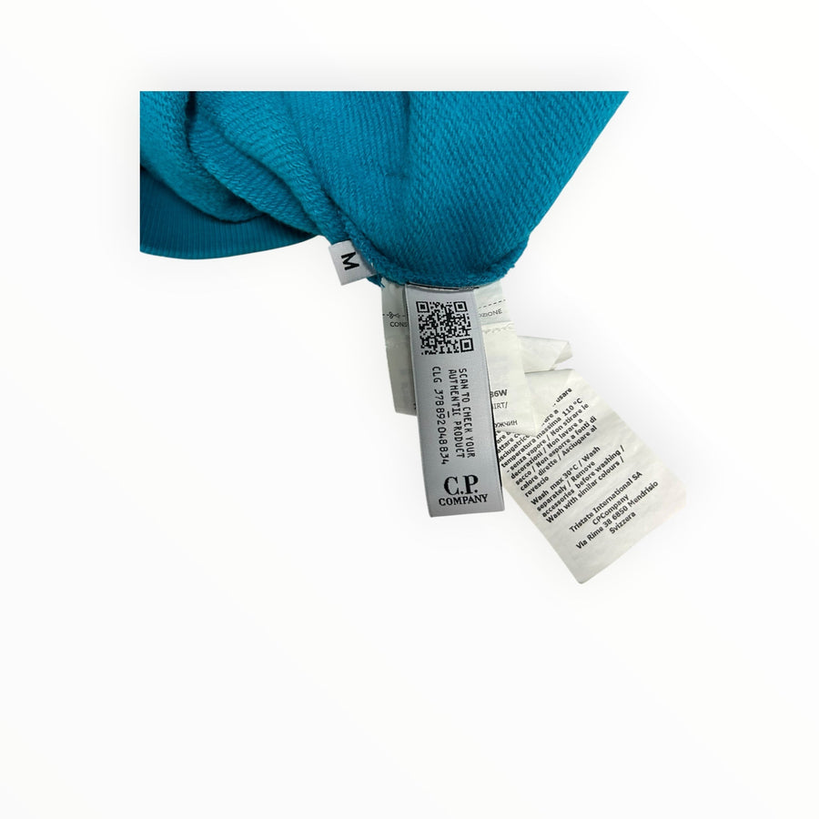Secondstore C.P. Company sweatshirt interior care label with QR code and size M tag on teal cotton fabric