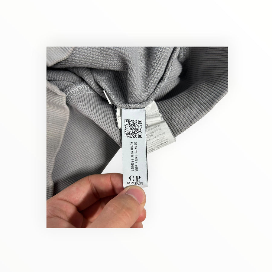 Secondstore C.P. Company sweatshirt interior label with QR code and authenticity details on grey cotton fabric