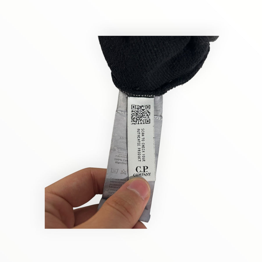 Secondstore C.P. Company black cotton sweatshirt care label with authenticity QR code held by a hand