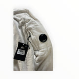 Secondstore C.P. Company off-white cotton sweatshirt sleeve featuring the iconic black lens pocket detail.