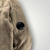Détail de la manche beige d'un sweat-shirt Secondstore C.P. Company avec la lentille emblématique sur poche zippée