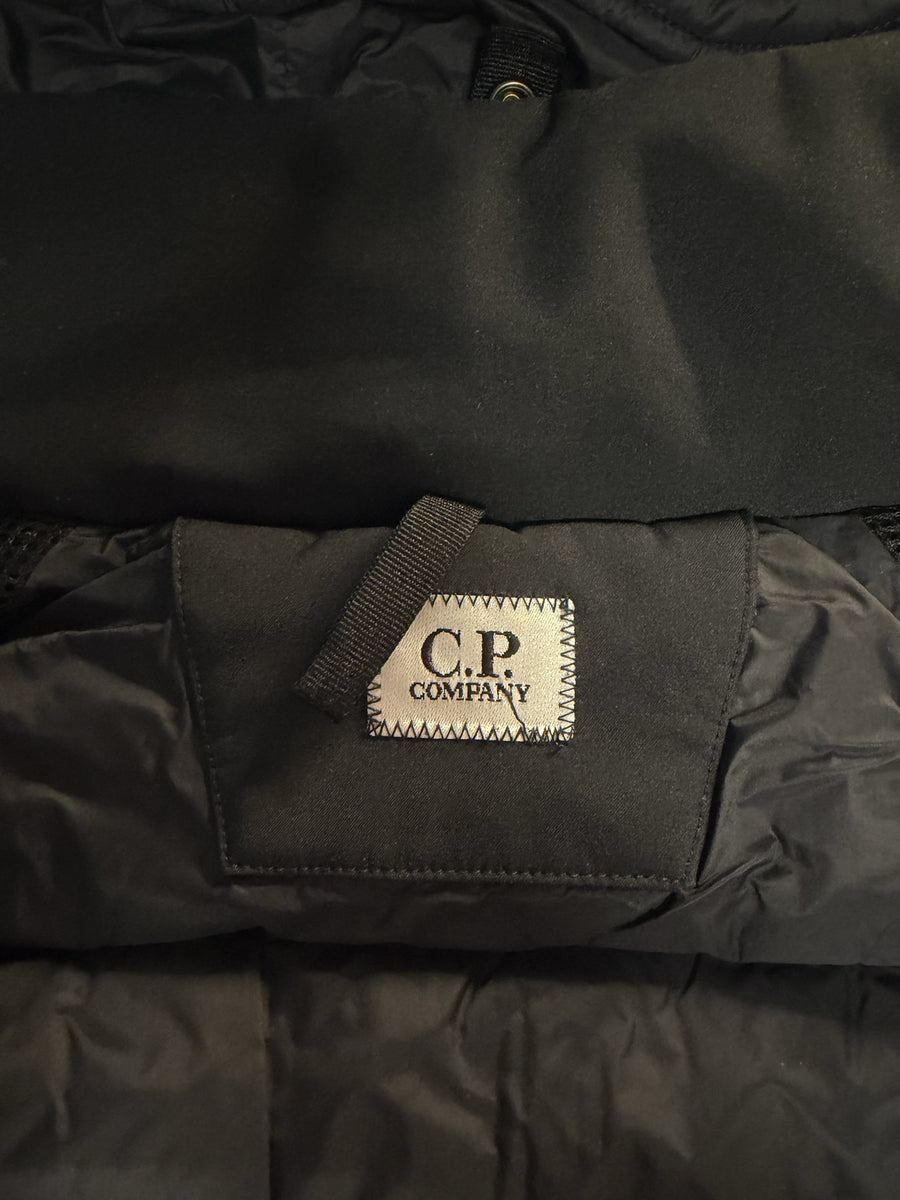 Étiquette de marque C.P. Company sur une veste noire technique Secondstore, détail de couture et tissu matelassé.