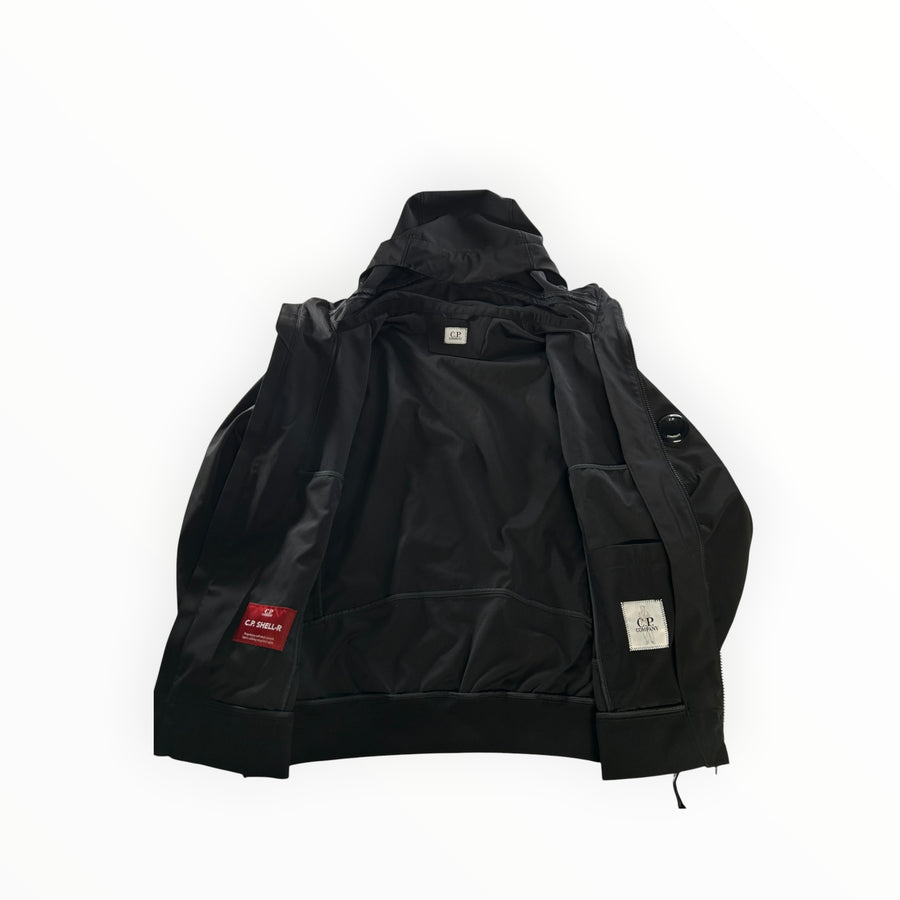 Veste noire Secondstore C.P. Company Shell-R zippée avec capuche, doublure technique et logo lentille sur la manche.