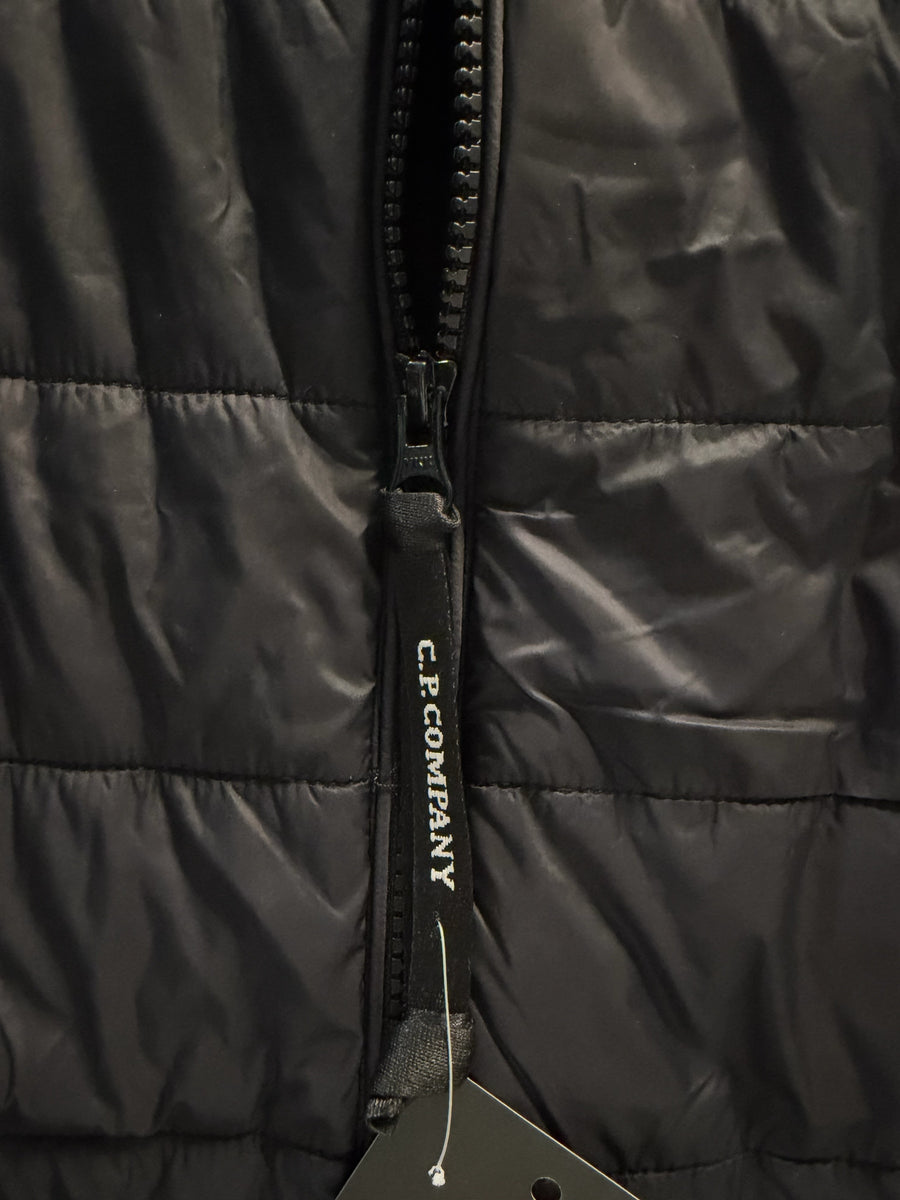 Gros plan sur la tirette zippée logotée de la veste noire matelassée Secondstore C.P. Company