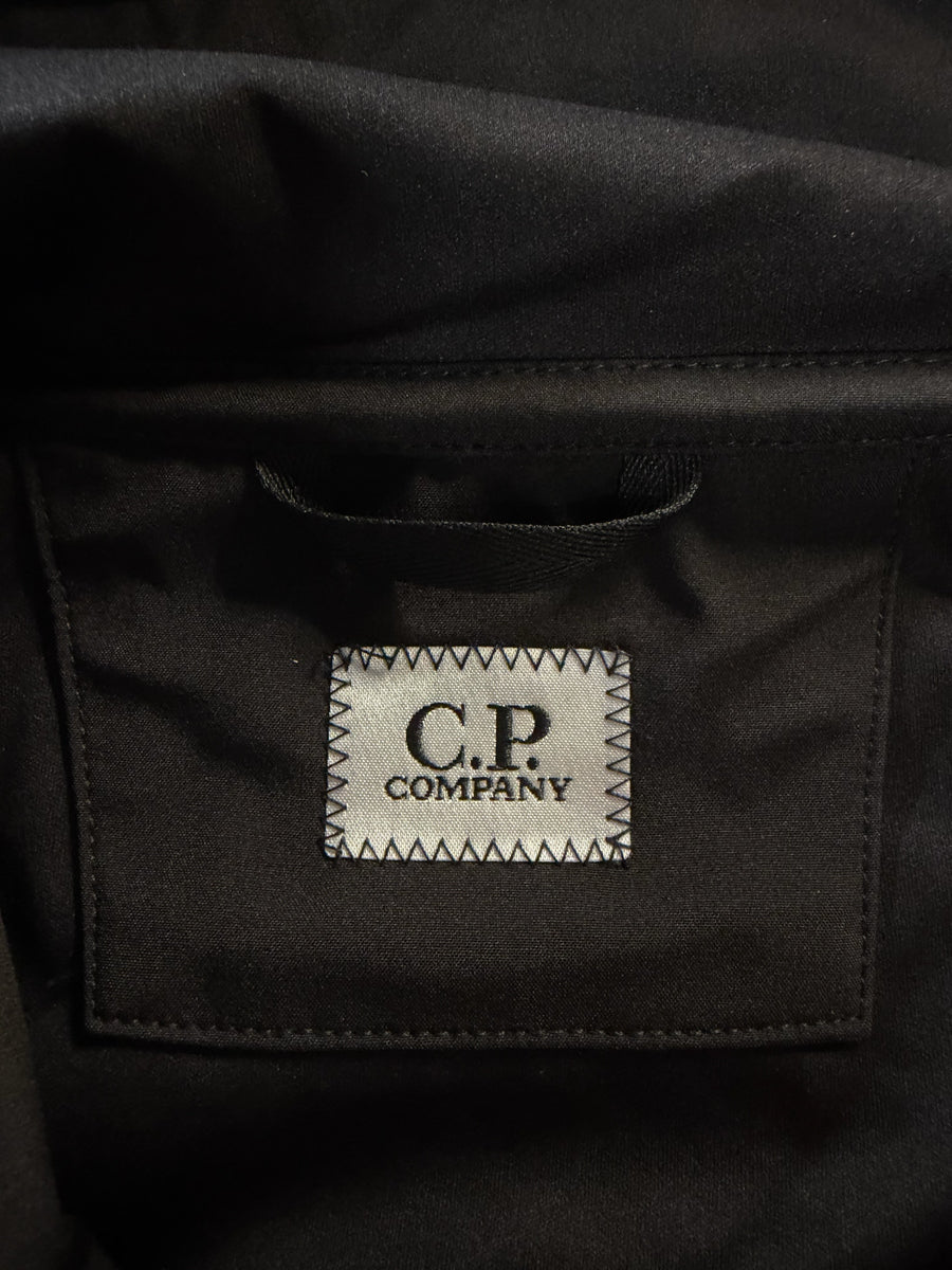Étiquette de marque C.P. Company cousue sur une veste noire en tissu technique, disponible chez Secondstore