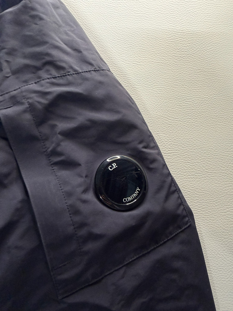 Détail de la manche d'une veste technique noire Secondstore C.P. Company avec le badge signature sur la poche