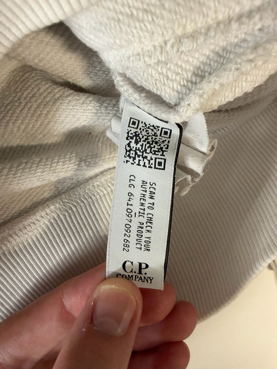 Étiquette d'authenticité Secondstore sur un sweat à capuche blanc cassé C.P. Company avec code QR et numéro CLG