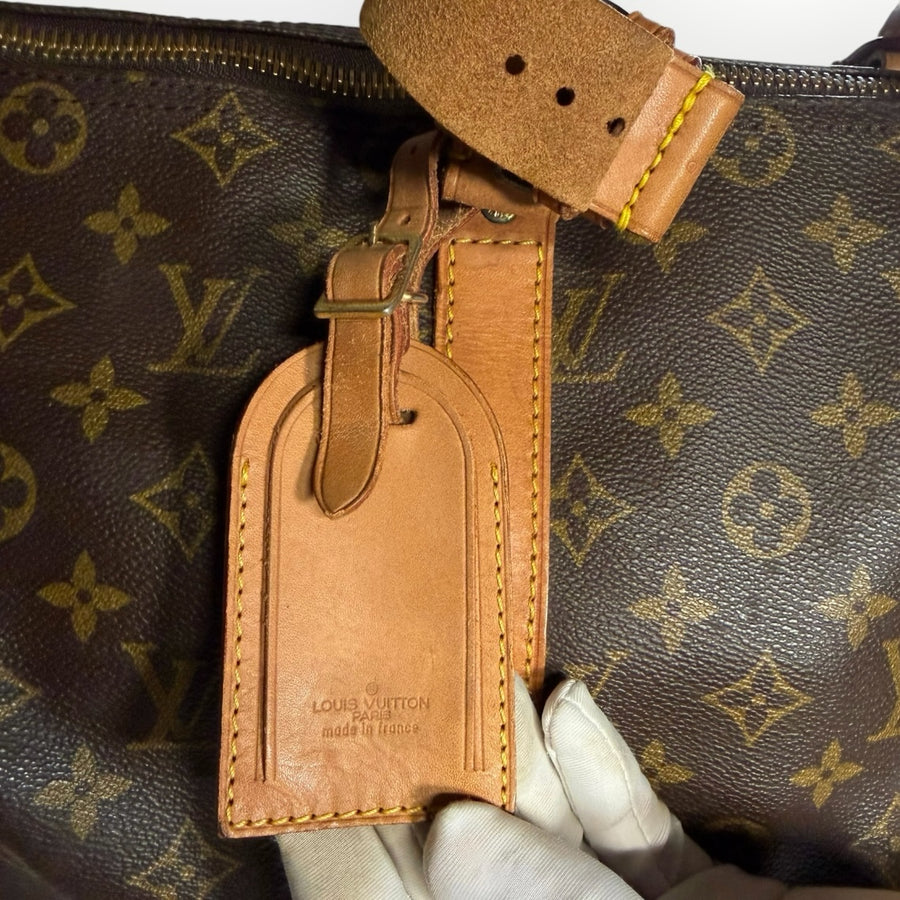 Etiquette de voyage en cuir naturel Secondstore sur un sac Louis Vuitton Keepall en toile Monogram marron
