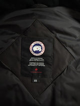 Étiquette intérieure noire avec logo Canada Goose sur un gilet Secondstore, indiquant la fabrication au Canada.