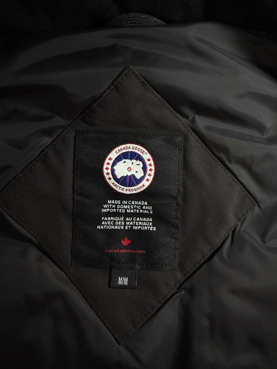 Étiquette intérieure noire avec logo Canada Goose sur un gilet Secondstore, indiquant la fabrication au Canada.