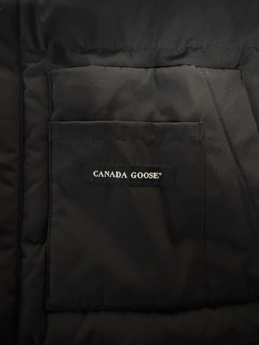 Gros plan sur la poche noire d'un gilet sans manches Secondstore Canada Goose avec étiquette logo brodée