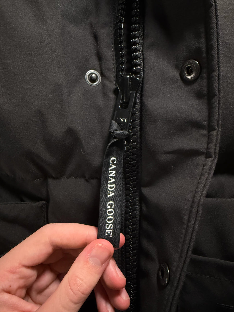 Gros plan sur la tirette de fermeture éclair noire avec logo Canada Goose sur un gilet Secondstore