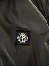 Gros plan sur le logo boussole emblématique de Secondstore sur un gilet sans manches Stone Island Junior vert olive