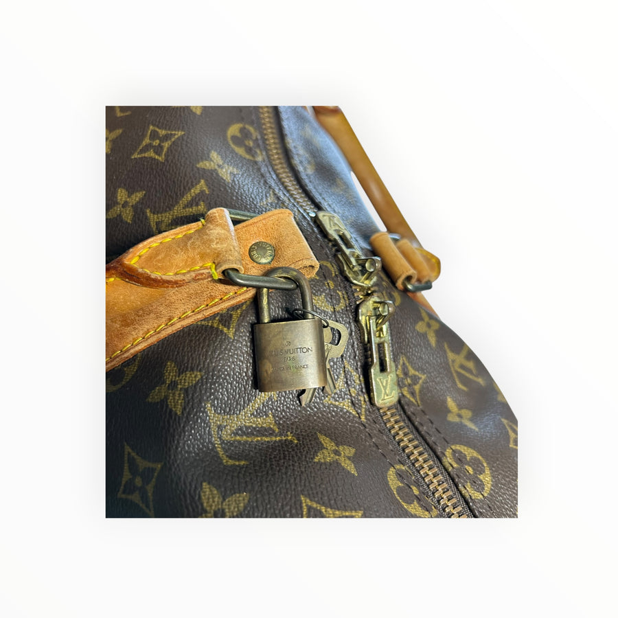 Détail du cadenas et de la fermeture éclair sur un sac de voyage Secondstore Louis Vuitton Keepall en toile Monogram