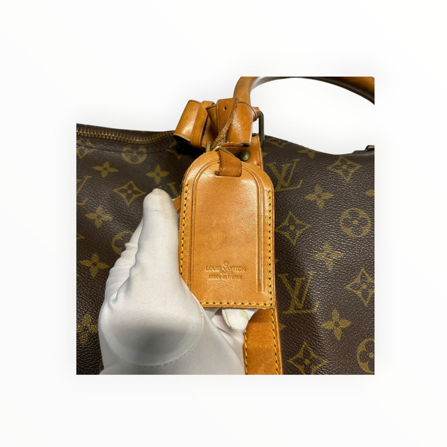 Détail de l'étiquette en cuir naturel sur un sac de voyage Secondstore Louis Vuitton Keepall en toile Monogram marron