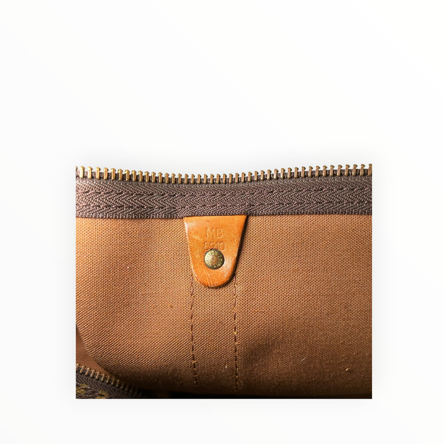Détail intérieur du sac de voyage Secondstore Louis Vuitton Keepall avec doublure textile et languette en cuir