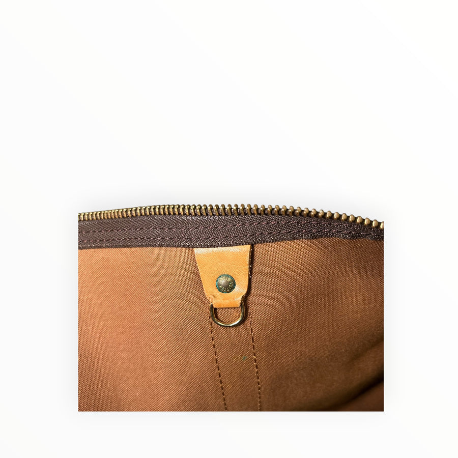 Détail intérieur du sac de voyage Secondstore Louis Vuitton Keepall avec doublure marron et rivet en métal doré
