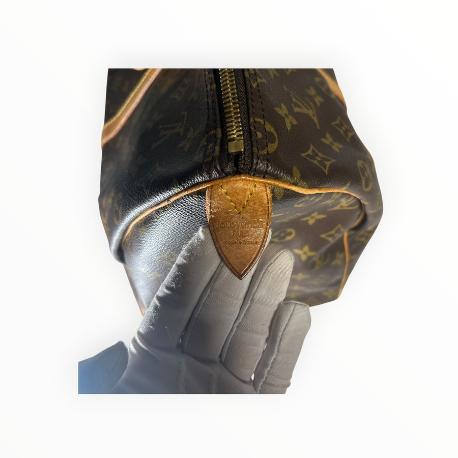 Gros plan sur le sac de voyage Secondstore Louis Vuitton Keepall en toile Monogram avec finitions en cuir naturel