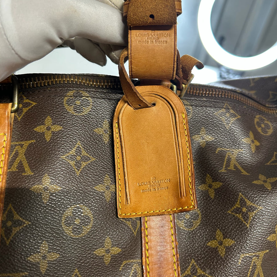 Détail du porte-adresse en cuir naturel sur un sac de voyage Secondstore Louis Vuitton Keepall en toile Monogram