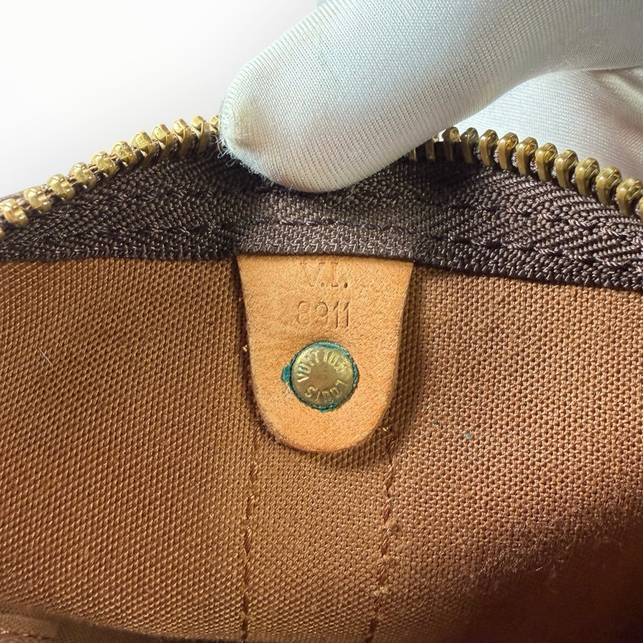 Gros plan sur le rivet en laiton gravé et le code date intérieur d'un sac de voyage Secondstore Louis Vuitton Keepall