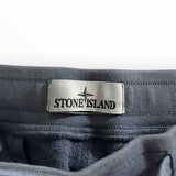 Gros plan sur l'étiquette logo Stone Island cousue sur la taille élastique d'un pantalon de jogging Secondstore gris