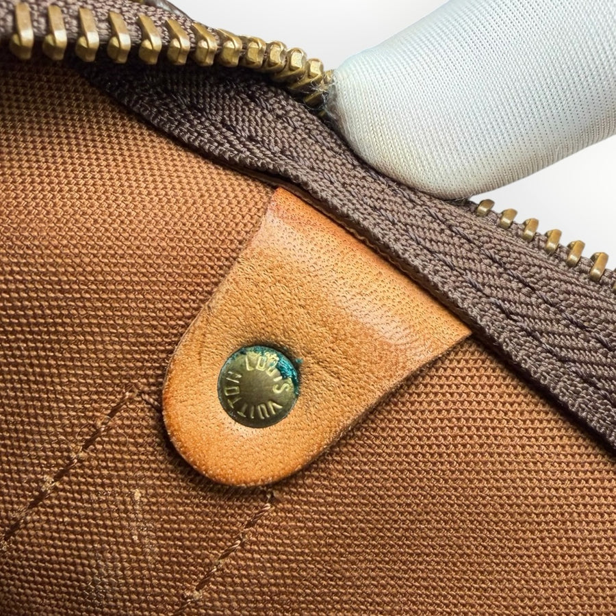 Détail du rivet en laiton gravé Louis Vuitton sur une garniture en cuir naturel du sac de voyage Secondstore Keepall
