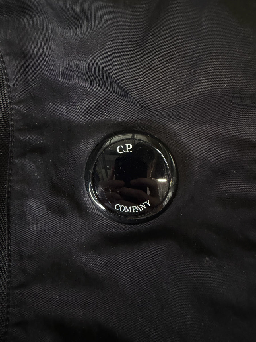 Détail de la lentille iconique noire sur un sac à dos en nylon Secondstore C.P. Company