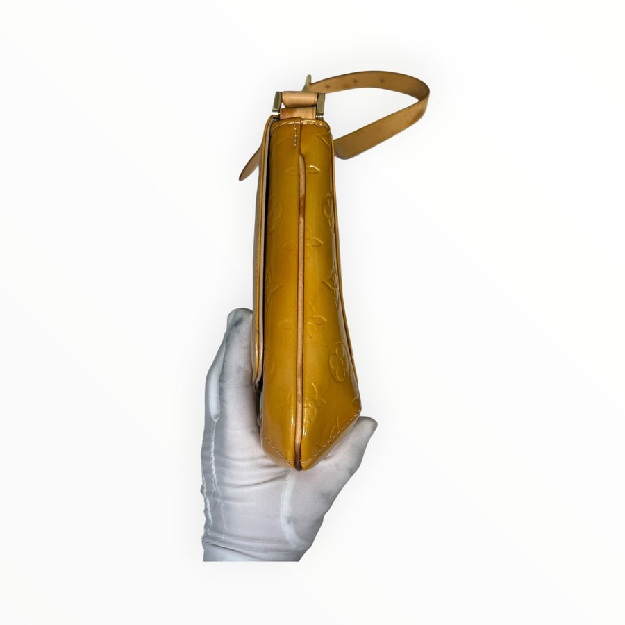 Sac à main Secondstore Louis Vuitton en cuir verni jaune Monogram embossé, vue de profil avec bandoulière en cuir.