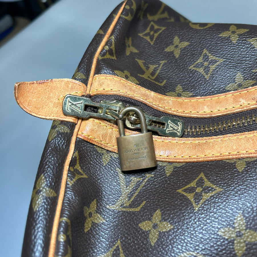 Détail du cadenas en laiton doré et fermeture éclair sur le sac de voyage Secondstore Louis Vuitton en toile Monogram