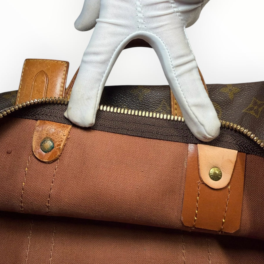 Détail de la fermeture éclair et des finitions en cuir du sac de voyage Secondstore Louis Vuitton Keepall en toile