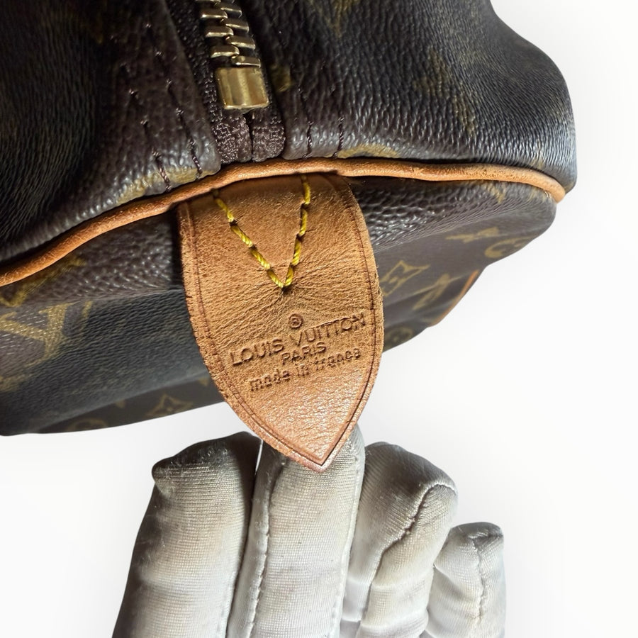 Détail du logo Louis Vuitton embossé sur le cuir d'un sac de voyage Keepall Secondstore en toile Monogram marron