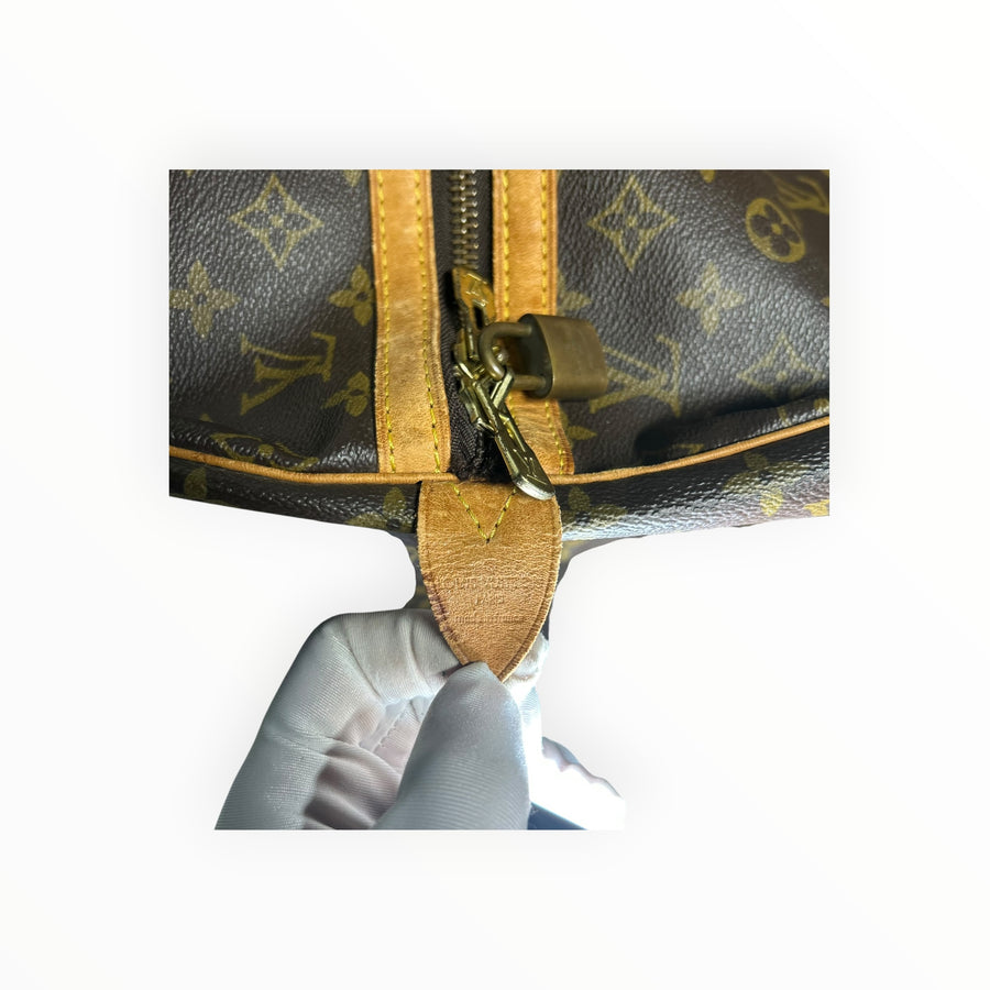 Gros plan sur la fermeture éclair et le cadenas en laiton du sac de voyage Secondstore Louis Vuitton Keepall Monogram