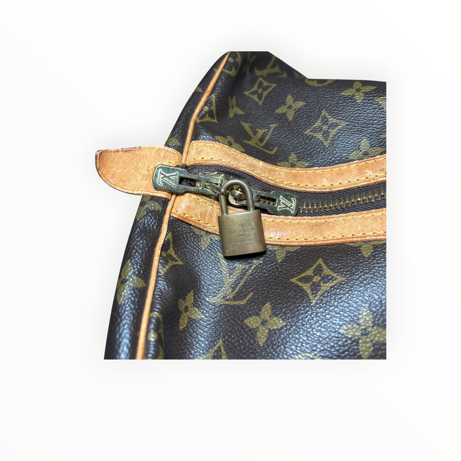 Détail du cadenas en laiton doré et fermeture éclair sur le sac de voyage Secondstore Louis Vuitton Keepall en toile Monogram marron.