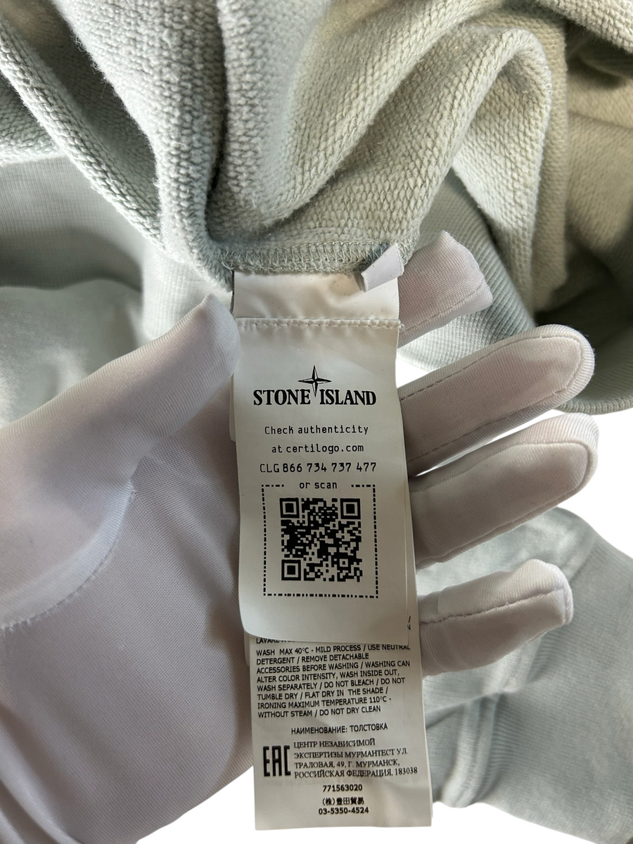 Secondstore Stone Island sweatshirt interior authenticity label with QR code and care instructions on sage green fabric