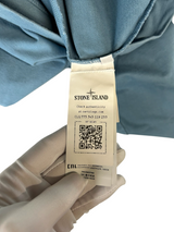Étiquette d'authenticité avec code QR et logo Stone Island sur un sweat-shirt bleu délavé chez Secondstore