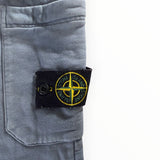 Gros plan sur le badge boussole emblématique Secondstore Stone Island sur un pantalon de jogging en coton gris bleuté