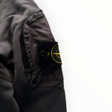 Gros plan sur la manche d'un sweat-shirt Secondstore Stone Island gris anthracite avec badge iconique et poche zippée