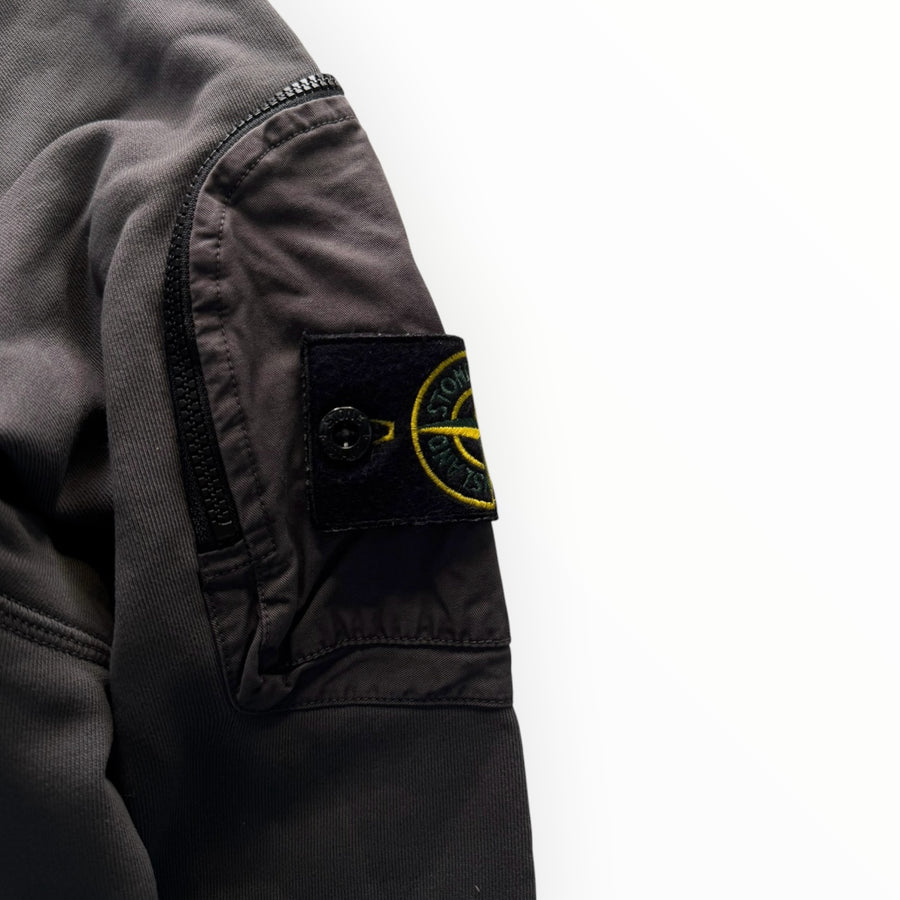 Gros plan sur la manche d'un sweat-shirt Secondstore Stone Island gris anthracite avec badge iconique et poche zippée
