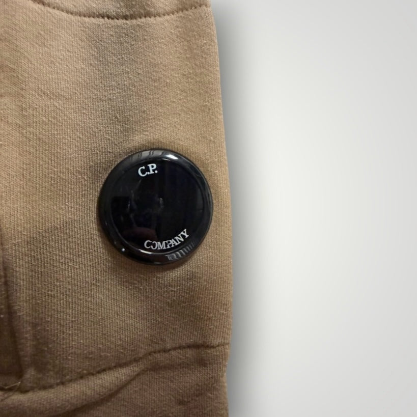 Détail de la lentille noire iconique C.P. Company sur la manche d'un sweat à capuche beige Secondstore en coton