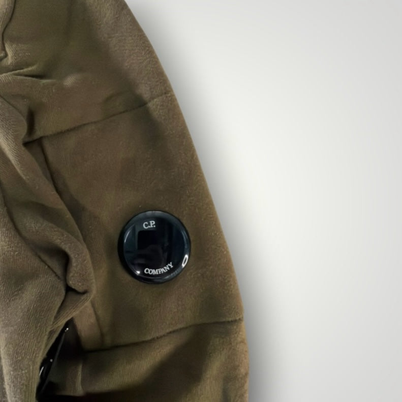 Détail de la manche d'un sweat-shirt kaki Secondstore C.P. COMPANY avec la lentille iconique sur poche zippée