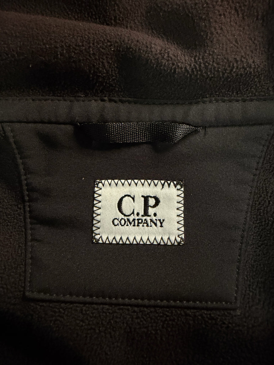 Étiquette de marque C.P. Company cousue à l'intérieur d'une veste noire en tissu technique chez Secondstore