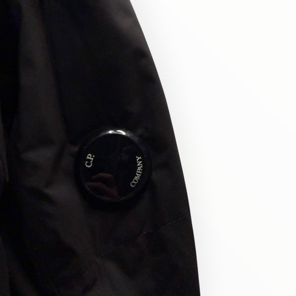 Détail de la manche d'une veste noire Secondstore C.P. Company avec l'emblématique lentille de protection