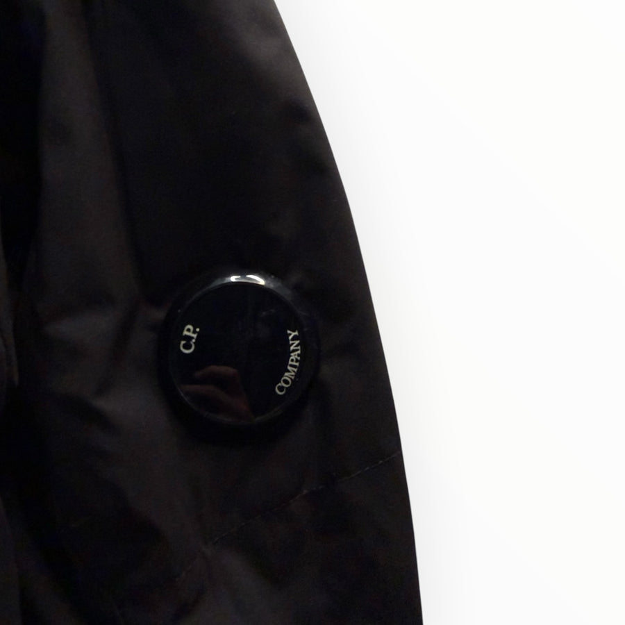 Détail de la manche d'une veste noire Secondstore C.P. Company avec l'emblématique lentille de protection