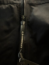 Gros plan sur la tirette de fermeture éclair noire marquée C.P. Company sur une veste technique Secondstore