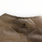 Gros plan sur le col rond et le matelassage en losanges beige de la veste Secondstore Converse avec logo brodé