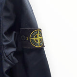 Badge boussole iconique Stone Island sur la manche d'une veste Secondstore bleu marine en tissu technique