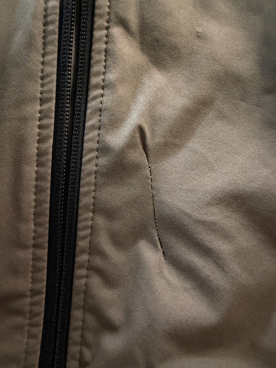 Gros plan sur le tissu technique Pro-Tek gris taupe d'une veste Secondstore C.P. Company avec fermeture éclair noire