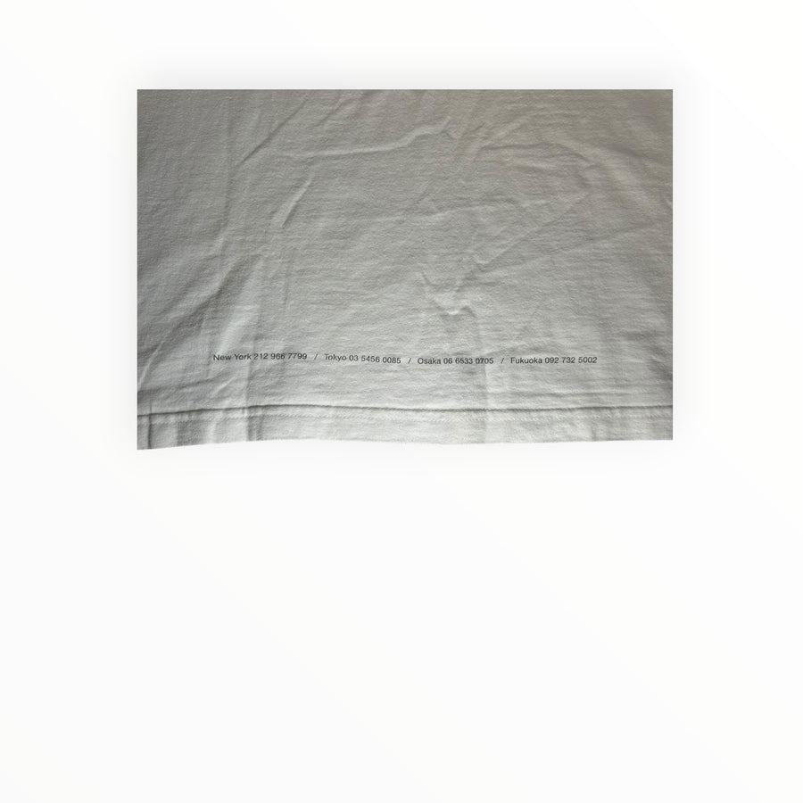 Secondstore white cotton t-shirt with back hem detail featuring printed store location phone numbers in black text